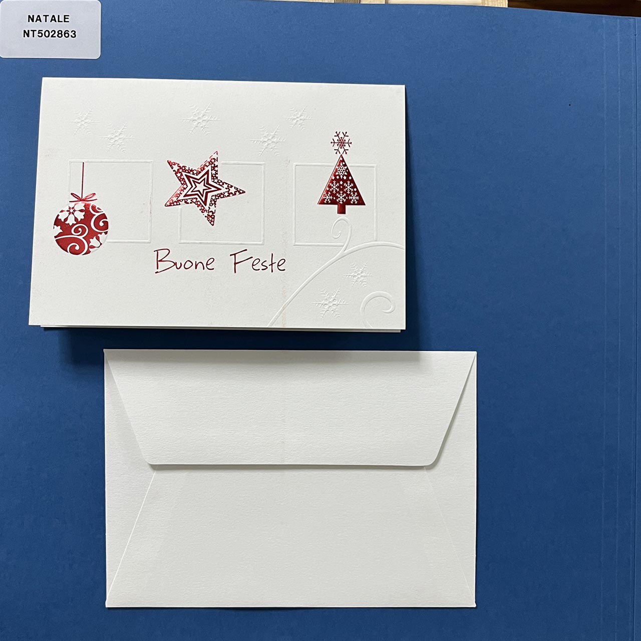 Elegante biglietto di Natale su carta martellata con particolari a rilievo tono su tono, personalizzabile all'interno. in copertina una simpatica illustrazione con piccoli particolari natalizi a rilievo, di colore rosso.