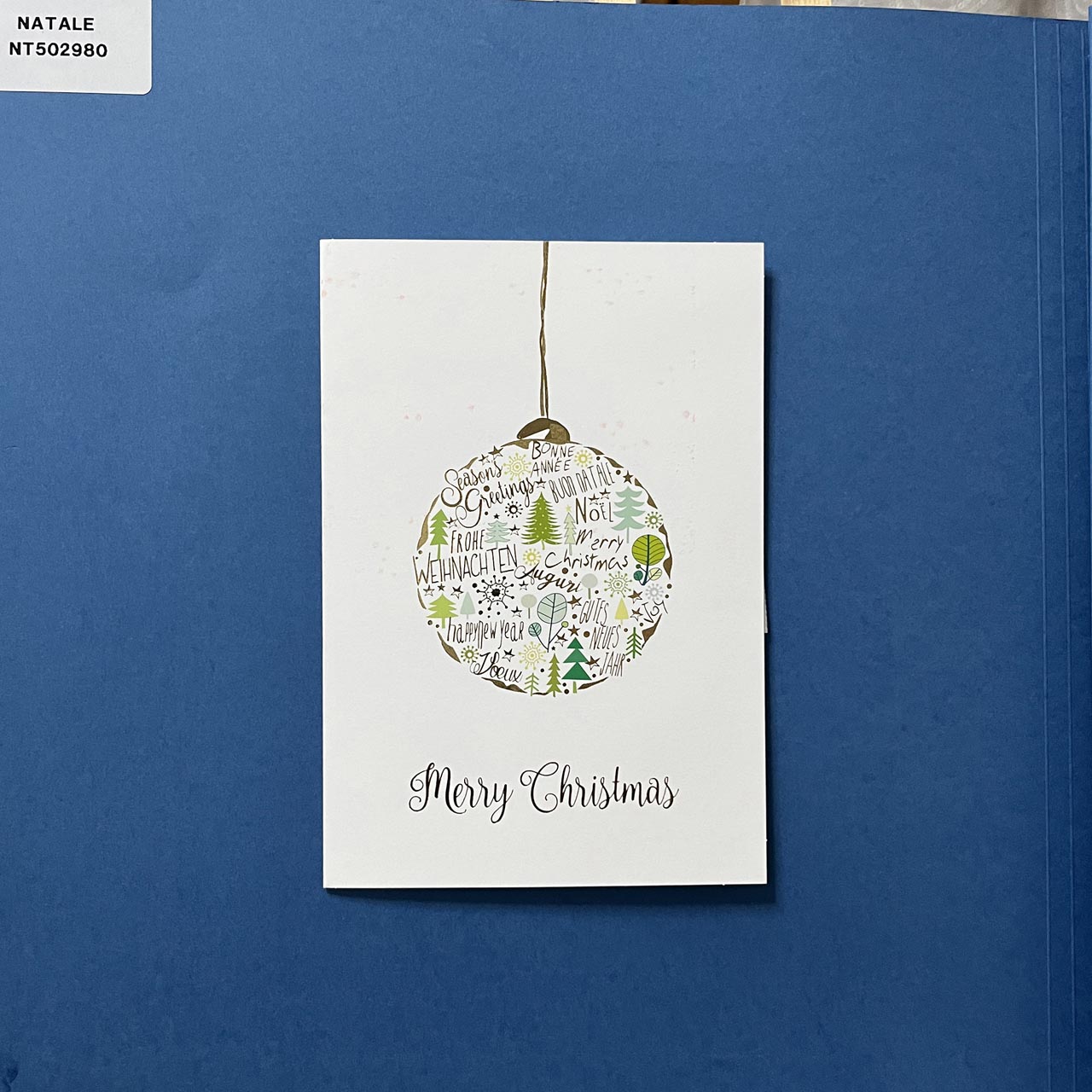Biglietto natalizio a libretto verticale. In copertina una palla di Natale decorata con particolari natalizi e la scritta ‘Merry Christmas’ a rilievo